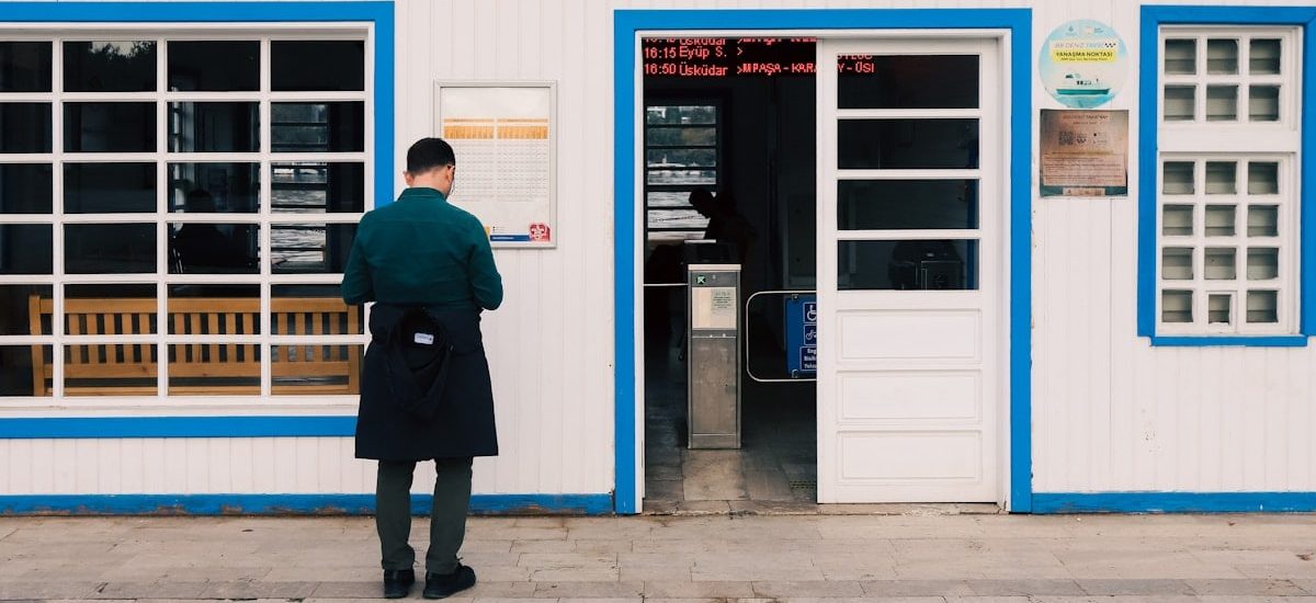 Man standing outside a ferry terminal building entrance.