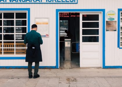 Man standing outside a ferry terminal building entrance.