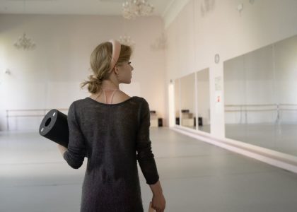 A ballet dancer holds gear in a spacious and elegant studio, ready for practice.